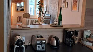A kitchen with a wooden countertop, a toaster, a kettle, and a coffee maker. There are hanging lights and a plant on the counter. - Large, cozy, quiet family apartment in the center of town, with view of the cathedral (Strasbourg)
