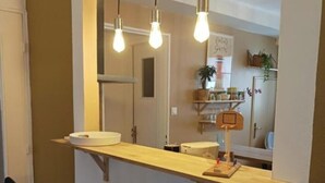 A kitchen with a wooden countertop, two black chairs, and hanging light bulbs. - Large, cozy, quiet family apartment in the center of town, with view of the cathedral (Strasbourg)