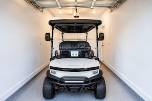 Ein weißer Golfwagen mit schwarzem Dach steht in einer Garage.