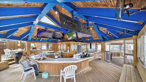 Eine großzügige Bar mit Holzbalkendecke und mehreren Bildschirmen.