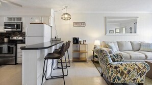 En kompakt opholdsstue med tekøkken, kaffabar og sofa.