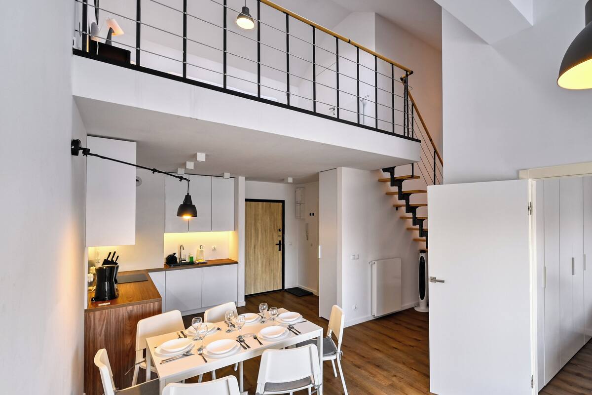 Un appartement moderne comprenant un coin repas, une cuisine et un escalier menant à l’étage supérieur.