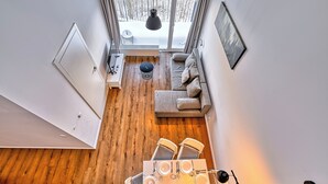 Un intérieur moderne avec un plancher en bois, un canapé, une table à manger avec des chaises et une vue sur un paysage enneigé par une grande fenêtre.