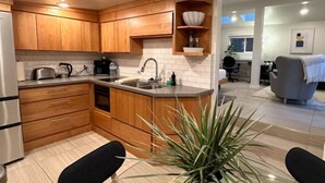 Een moderne keuken met houten kasten, een geïntegreerd eiland en een eetgedeelte met een plant.