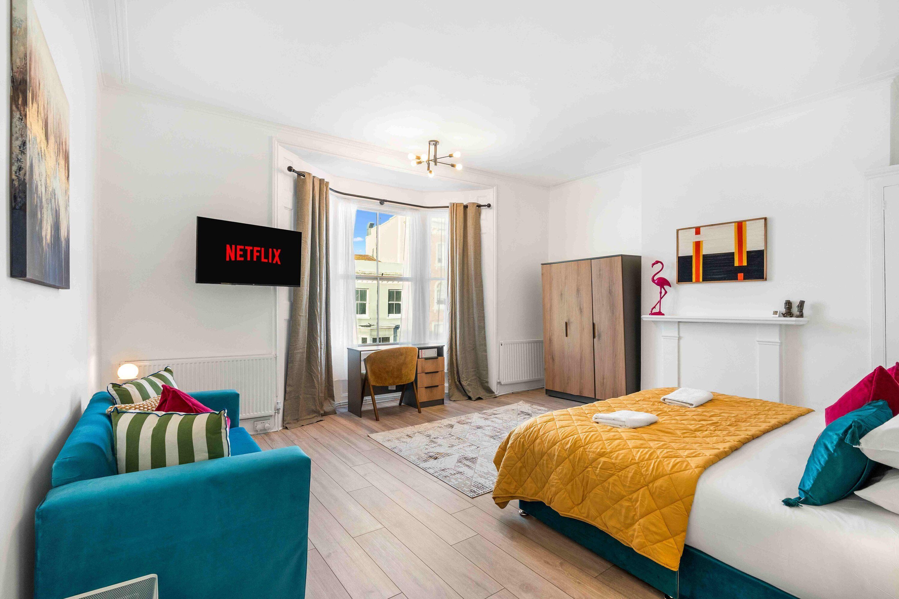 Een moderne hotelkamer met een bed, een bureau, een stoel, een televisie en een kledingkast.