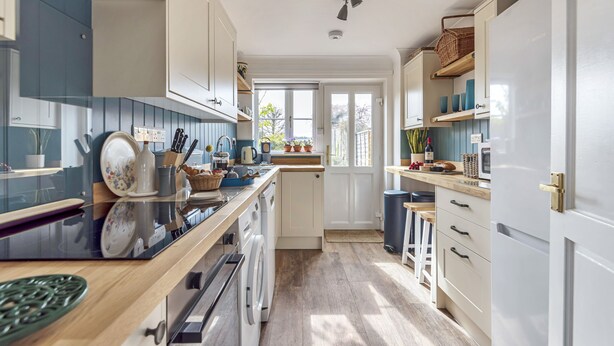 A kitchen with a wooden countertop, white cabinets, and a view of the outdoors. - 4 Hare Cottage - sleeps 4 guests  in 3 bedrooms (South Creake)