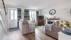 A living room with two sofas, a coffee table, a TV, and a wooden floor. - 4 Hare Cottage - sleeps 4 guests  in 3 bedrooms (South Creake)