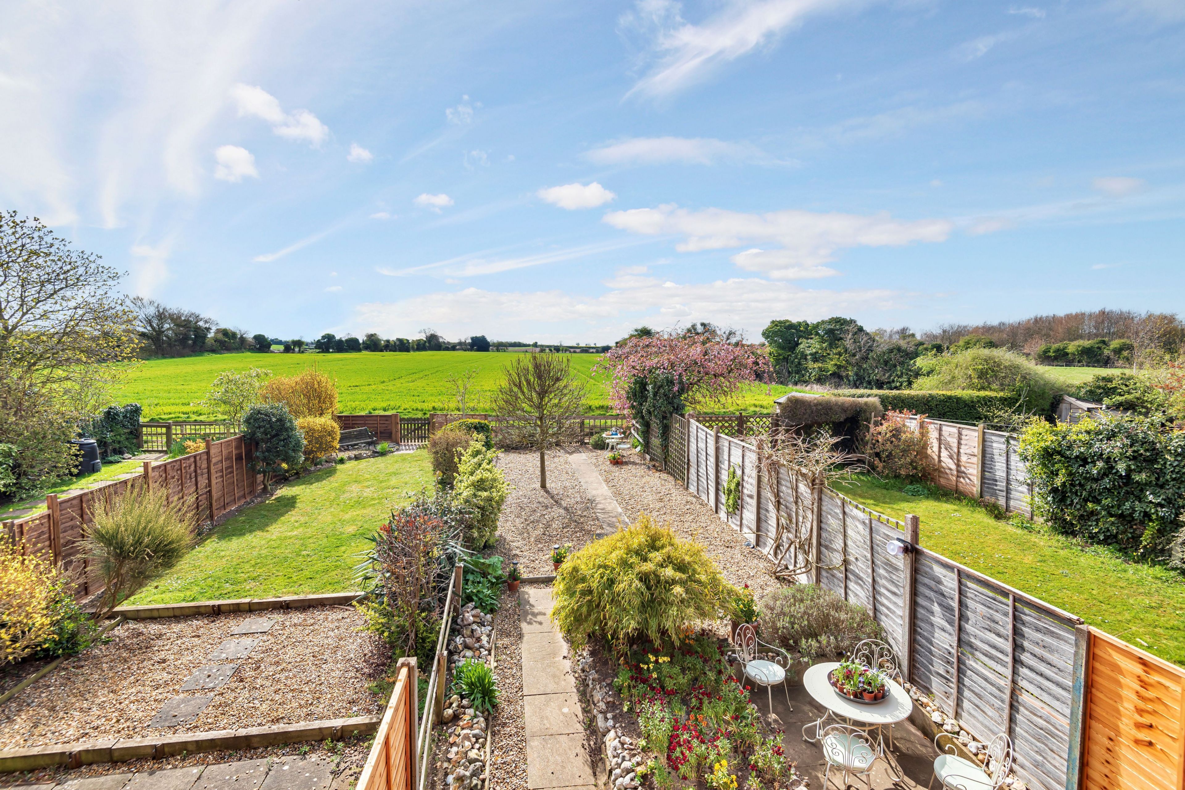A well-maintained garden with a patio area, a wooden fence, and a variety of plants.