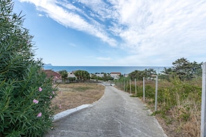 A paved pathway leading to a coastal area with houses and trees. - Josade Blu Mare Apartment with Sea View, Wi-Fi, and Air Conditioning (Alcamo)
