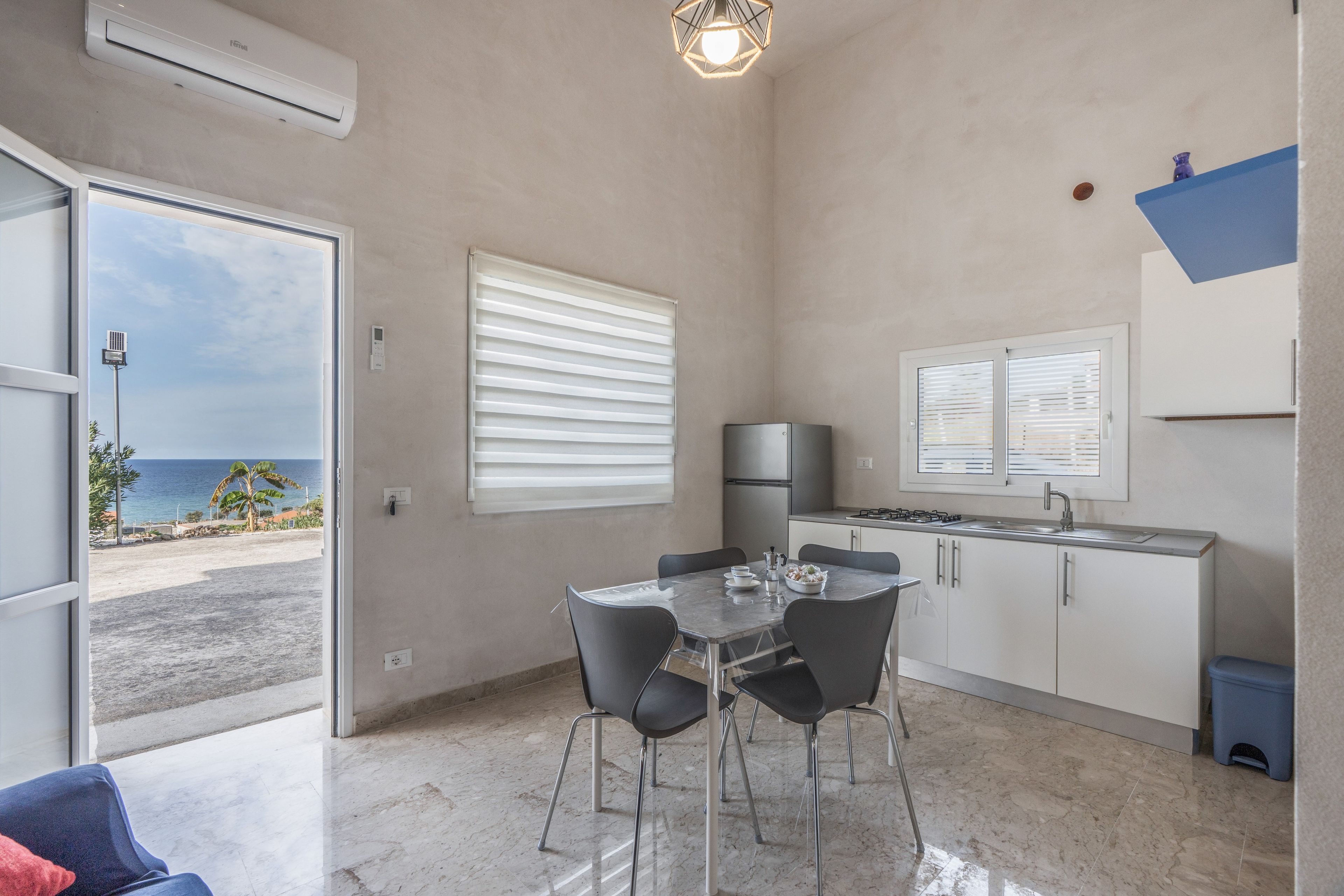 A compact kitchen with a dining area, a view of the sea, and a modern design.