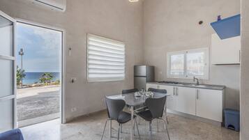 A compact kitchen with a dining area, a view of the sea, and a modern design.