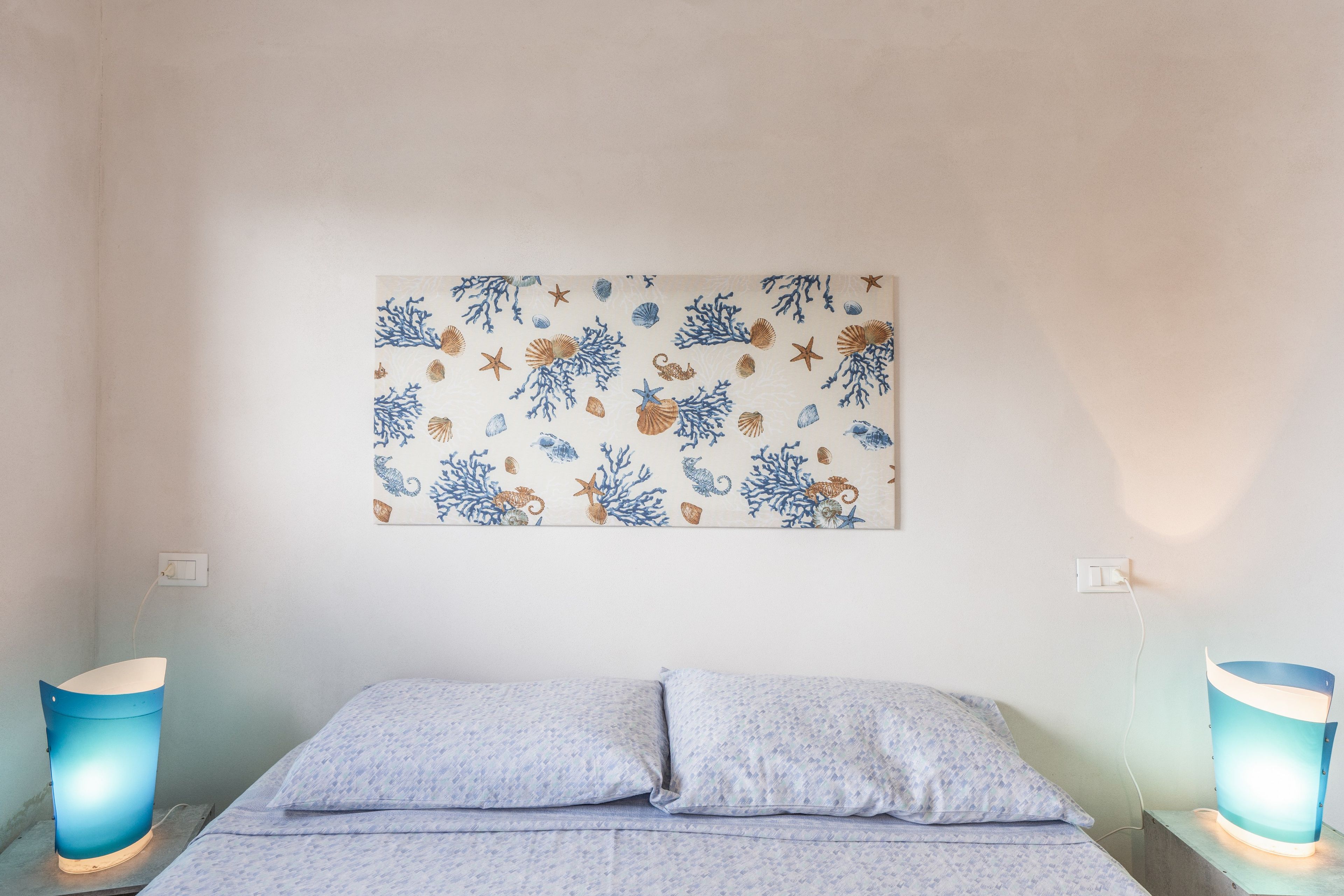 Una camera da letto con un letto, due lampade da comodino e un'opera d'arte appesa al muro.