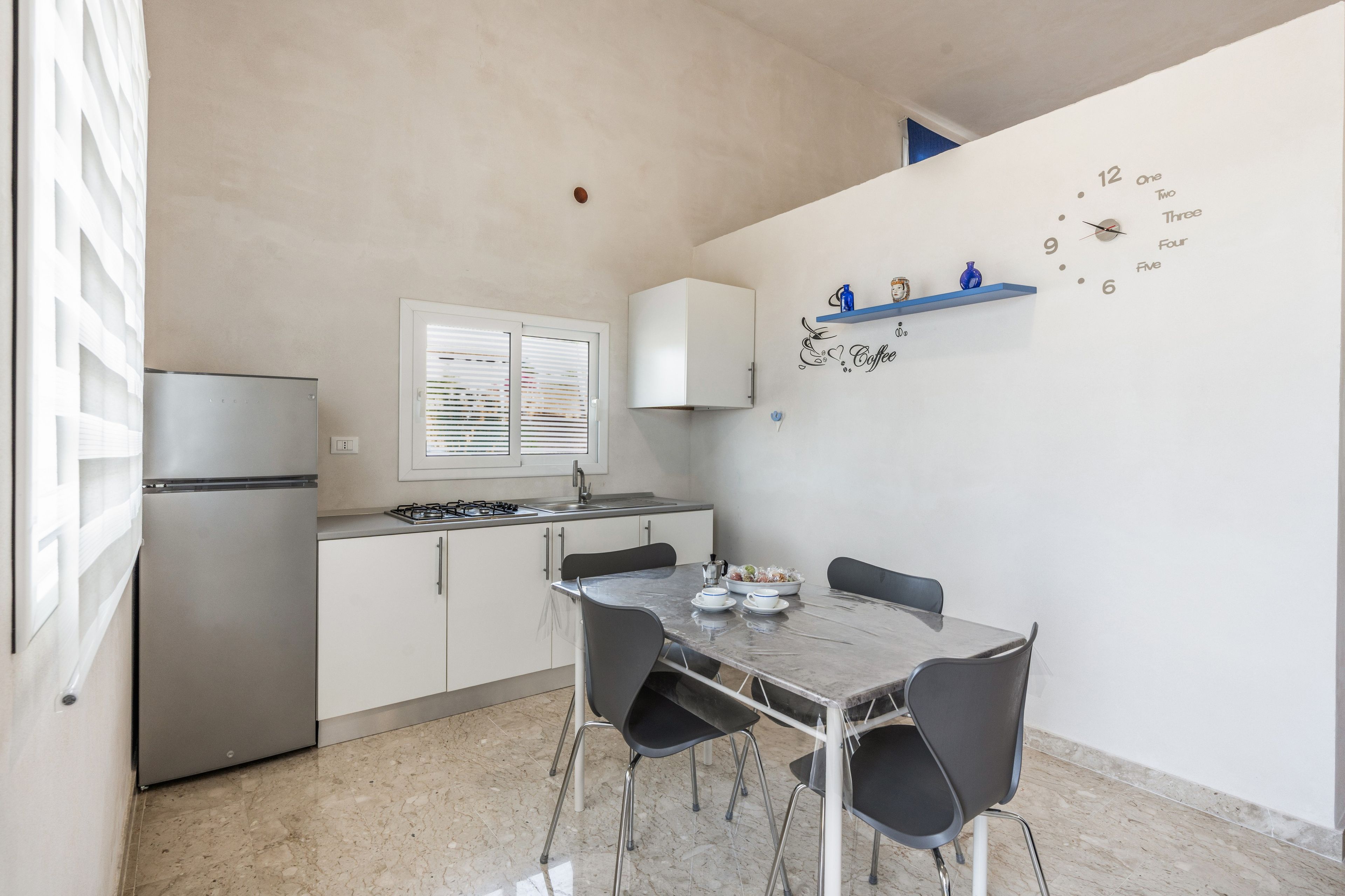 Una cucina compatta con frigorifero, fornello e un tavolo da pranzo con sedie.