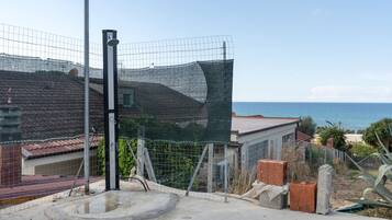A fenced area with a concrete structure, a metal pole, and a view of the sea.