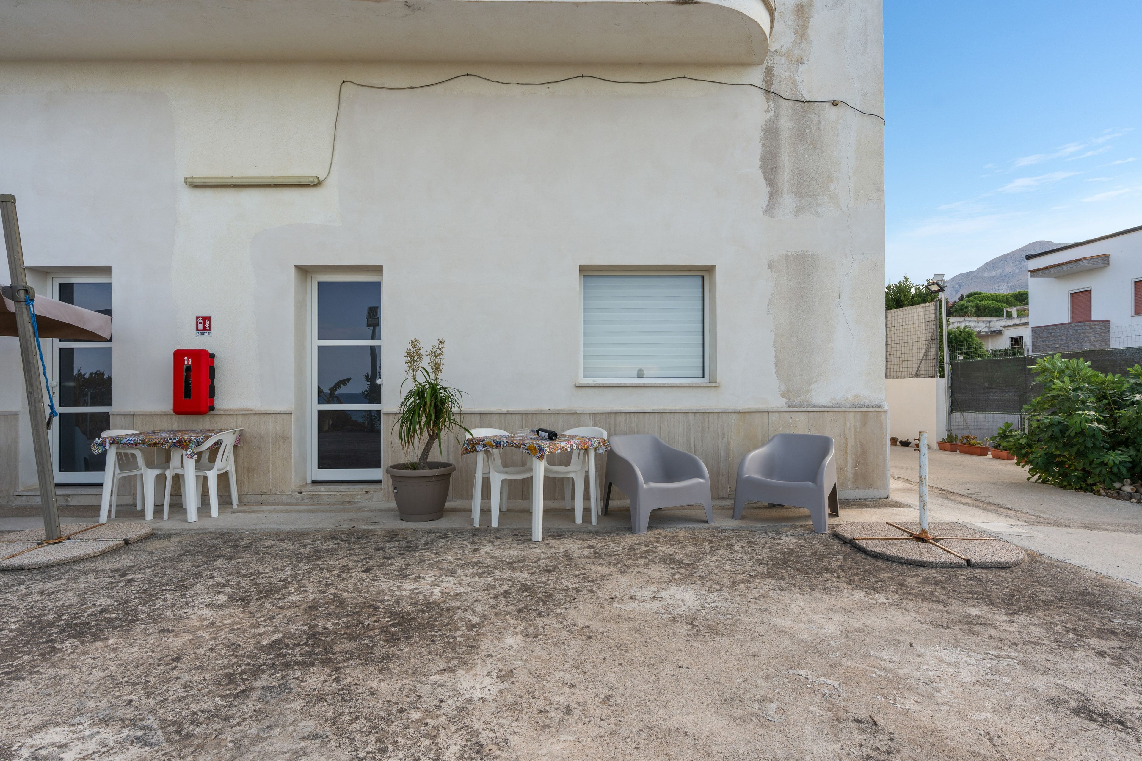 A building with a white exterior, a door, a window, and a small balcony area with a table and chairs.