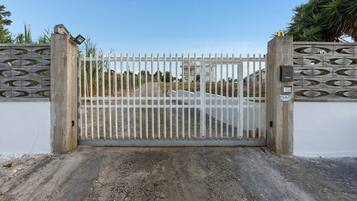 A gated entrance with a metal gate and a concrete wall with decorative cutouts.