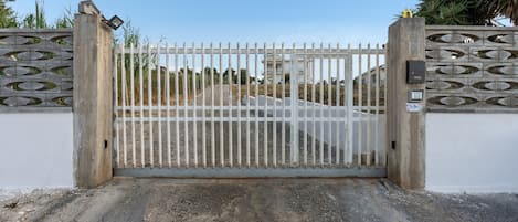 En lukket indgang med en metalport og en betonmur med dekorative udskæringer.