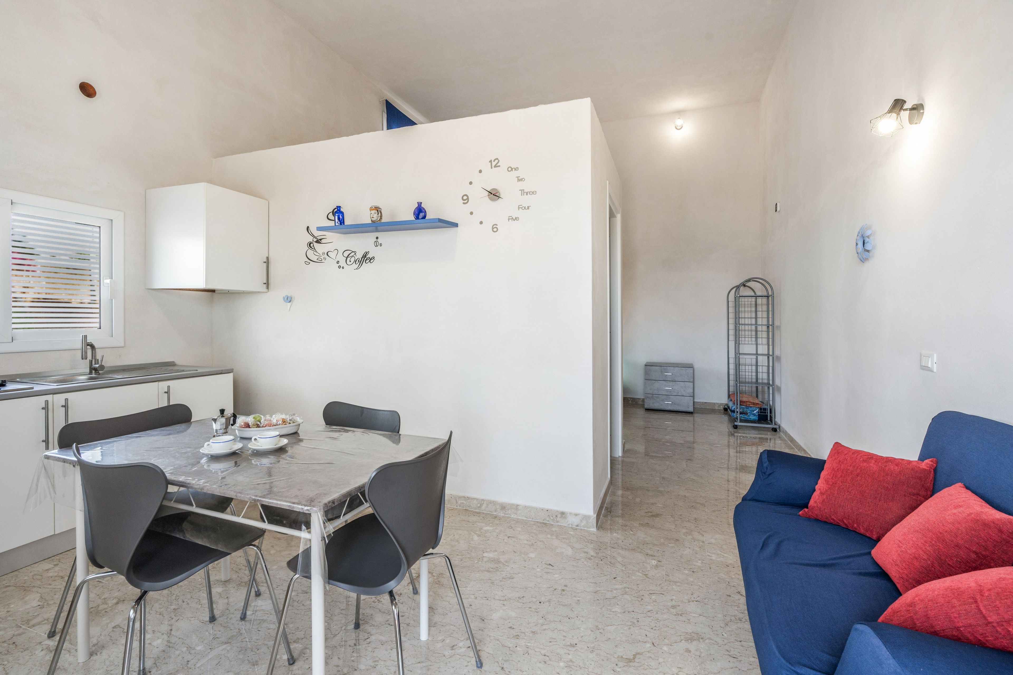 Une cuisine moderne avec une table à manger et des chaises, un coin café et un espace de détente avec un canapé et des coussins.