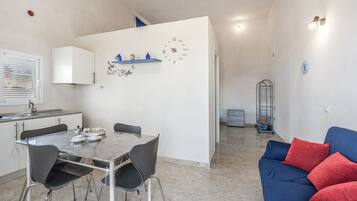 Une cuisine moderne avec une table à manger et des chaises, un coin café et un espace de détente avec un canapé et des coussins.