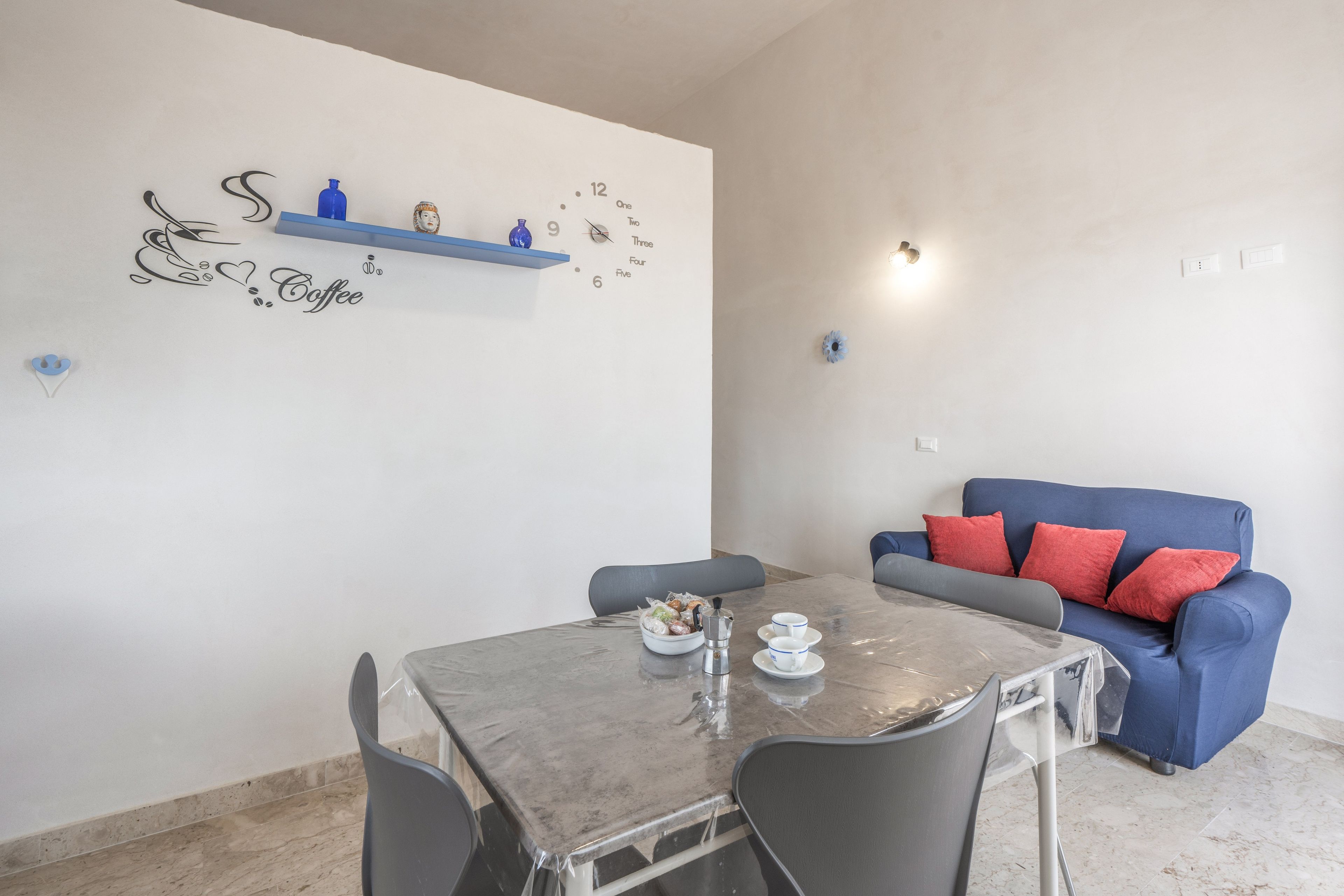 Zona pranzo con tavolo, sedie e decorazione murale a tema caffè.
