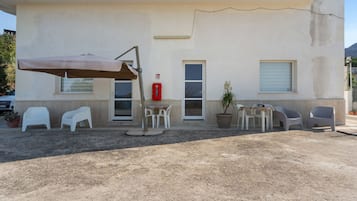 Een gebouw met een patio met buitenmeubilair, een brandblusser en een bloempot.
