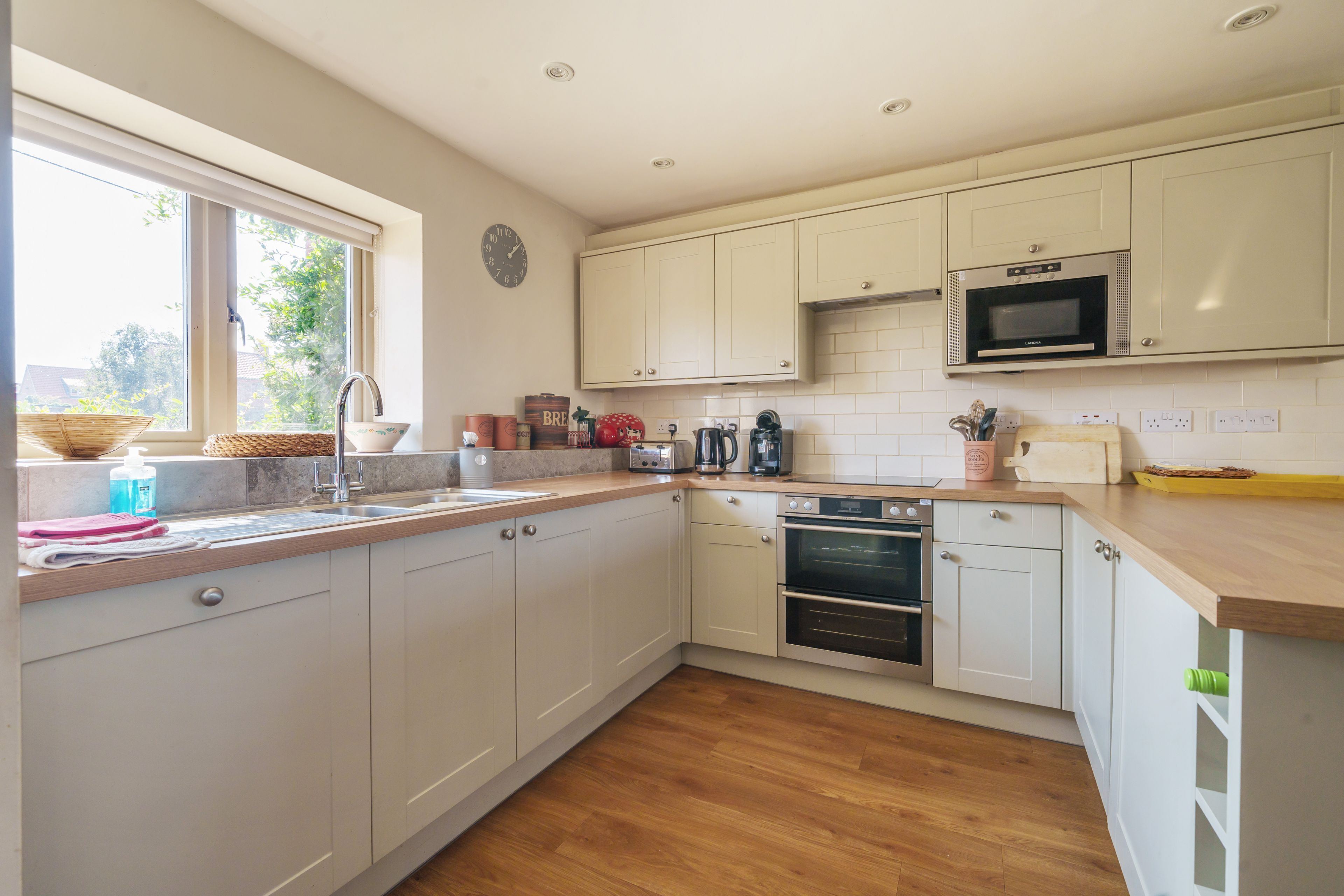 A modern kitchen with white cabinets, a microwave, an oven, and a window providing natural light.