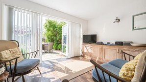 A modern living room with a TV, wooden cabinets, and a large sliding glass door leading to a patio.