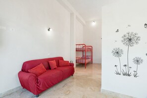 A red sofa with pillows, a bunk bed, and a wall with dandelion illustrations.