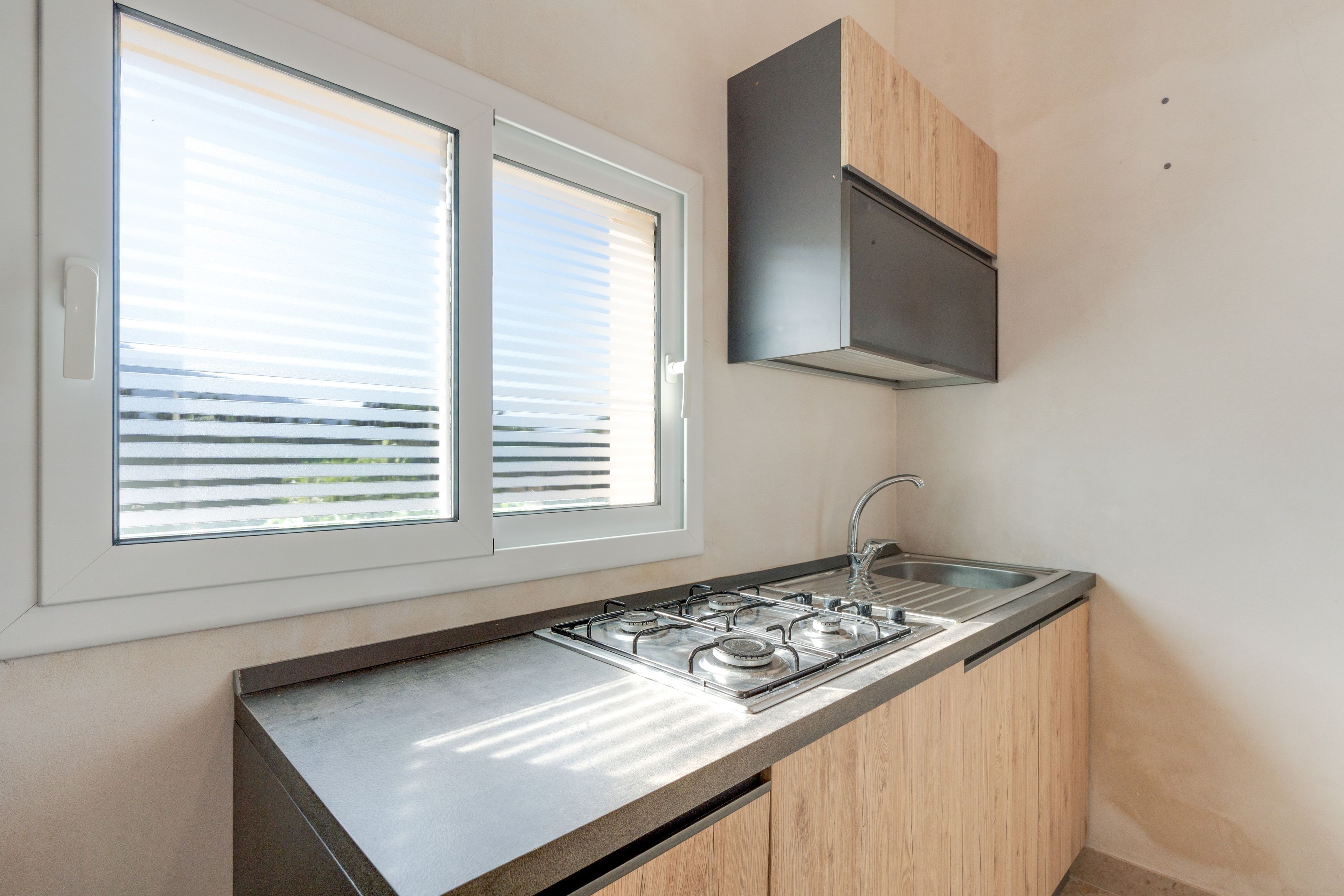 Una cucina moderna con piano cottura a gas integrato, lavello in acciaio inox e pensili in legno.