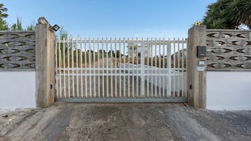 Une entrée fermée par un portail en métal et un mur en béton orné de motifs décoratifs.