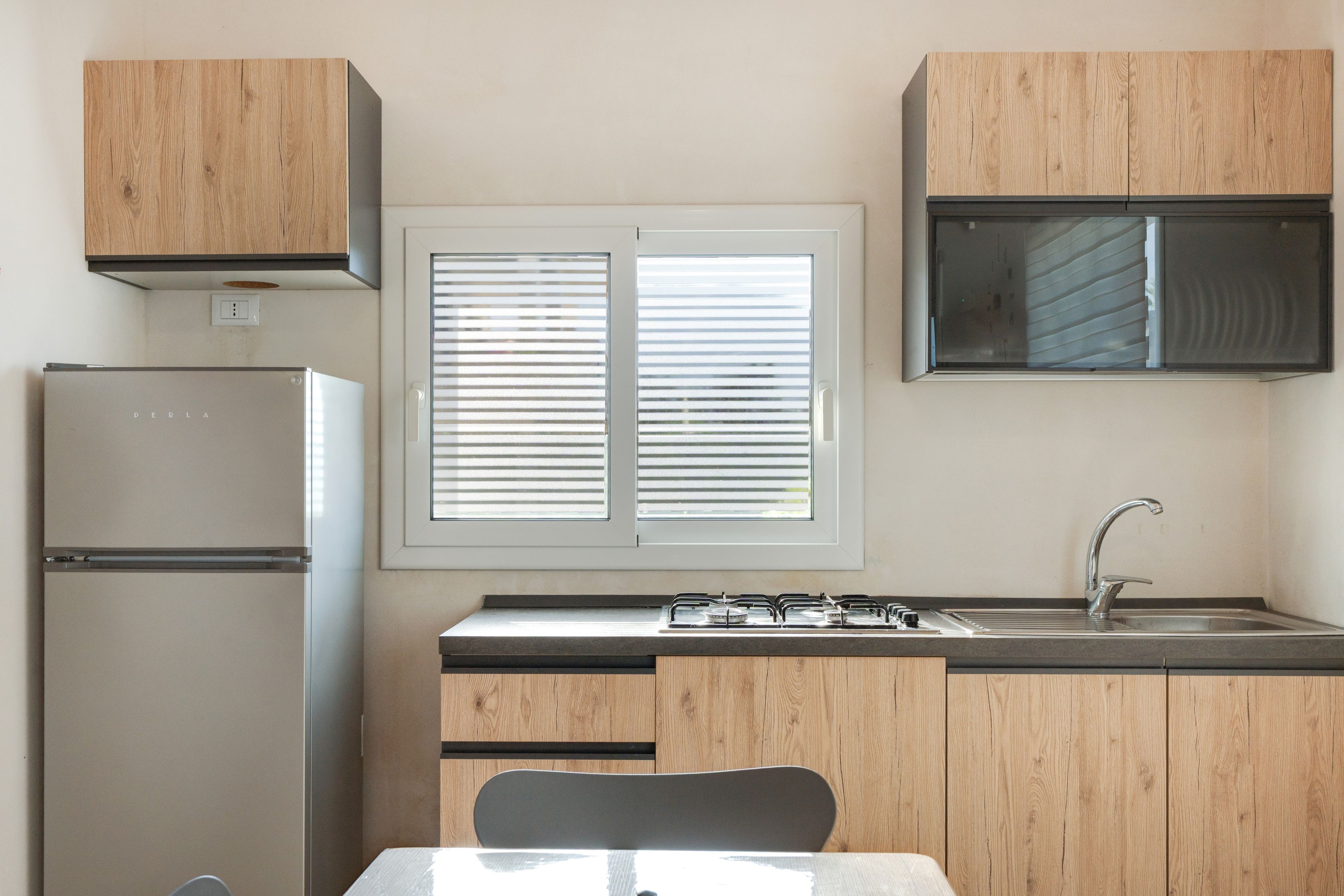 Une cuisine de taille réduite, équipée d’un réfrigérateur, d’une cuisinière, d’un évier et de meubles de rangement en bois.