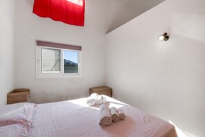 A bedroom with a bed, a window, a nightstand, and a wall-mounted light fixture. - Apartment 'Josadè Rosso Corallo' with Sea View, Wi-Fi and Air Conditioning (Alcamo)