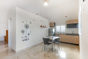 A modern kitchen with a dining area, featuring a dandelion wall decal, a built-in oven, and a large window.
