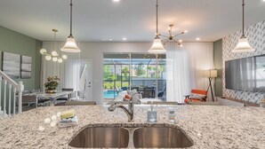 A modern kitchen with granite countertops, stainless steel sink, and pendant lighting. - 5BR Solterra Villa, Pool & Jacuzzi (Davenport)