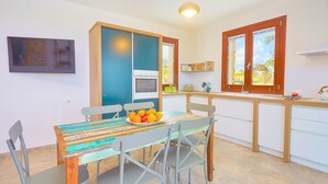 Een moderne keuken met een eettafel, stoelen en een schaal met fruit.