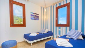 Een kamer met twee bedden, een klein voetenbankje en een schilderij aan de muur.