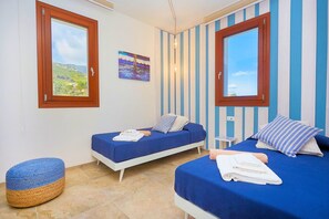 Ein Zimmer mit zwei Betten, einem kleinen Hocker und einem Bild an der Wand.