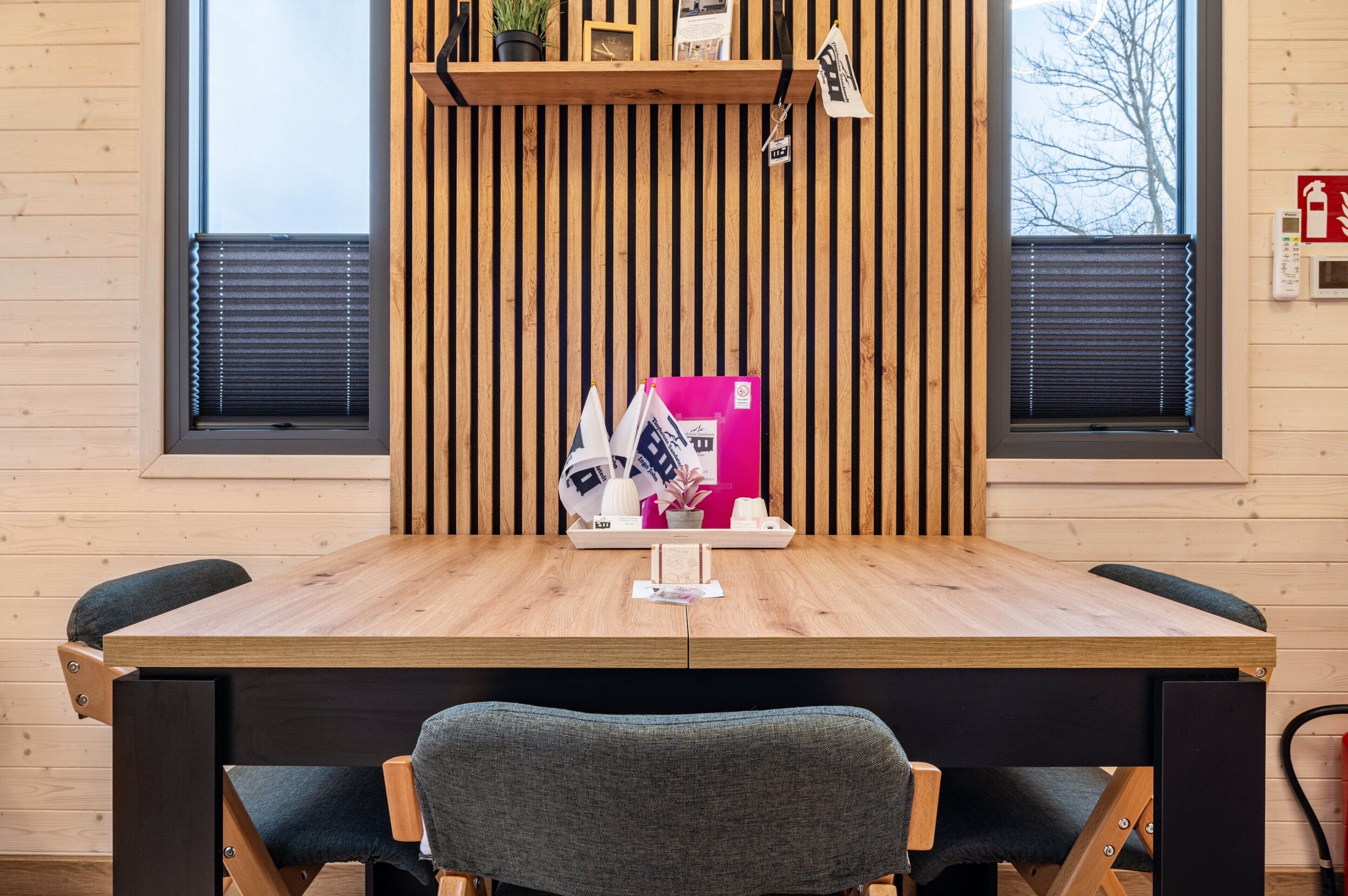 Een houten tafel met tijdschriften, een plantje en een dienblad met een glas.