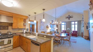 A spacious kitchen with wooden cabinets, a central island, and a dining area with a chandelier. - Luxury 2-Bed Penthouse w/ Home Office (Crested Butte)