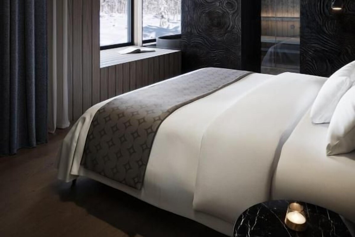 Quarto moderno com cama grande, janela com vista e parede com padrão escuro.