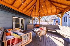 A covered outdoor deck with a wooden bench, a small table, and a wicker chair. - Boise Boho - Hot Tub - Peaceful Retreat (Boise)