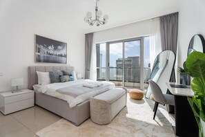 A modern bedroom with a large bed, a desk, a chair, and a balcony with a city view. - Restful 2BR at Dubai Marina (Dubai)
