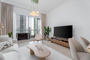 Ein modernes Wohnzimmer mit Flachbildfernseher, einer Couch, einem Couchtisch und einem Essbereich mit Tisch und Stühlen.