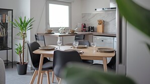 Eine moderne Küche mit Esstisch für zwei Personen, einem Blumentopf und einem Fenster, das natürliches Licht hereinlässt.