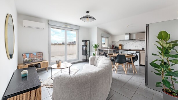 Eine moderne Wohnung mit Wohnzimmer, Essbereich und Küche. Es gibt ein großes Fenster, einen Deckenventilator und einen Blumentopf.