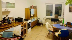 A compact kitchen with a dining area, a window with a view, and a ceiling fan. - Room 'Mondzimmer' with Wi-Fi (Kassel)