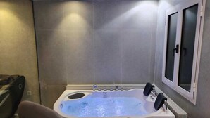A modern bathroom with a large bathtub, a window with frosted glass, and a wooden table. - HAYAT ROSE AL Madinah AL Munawwarah  (Madinah)