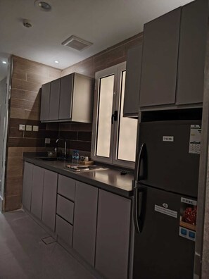 A modern kitchen with grey cabinetry, a stainless steel refrigerator, and a built-in oven. - HAYAT ROSE AL Madinah AL Munawwarah  (Madinah)