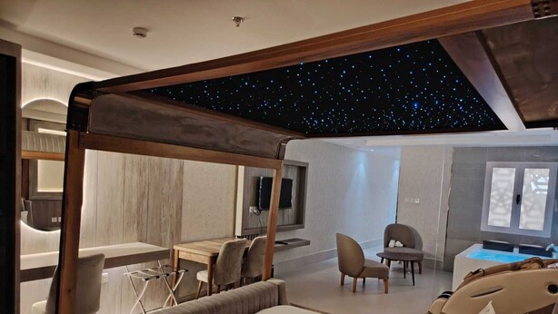 A modern hotel room with a starry ceiling, a large bed, a desk, and a seating area. - HAYAT ROSE AL Madinah AL Munawwarah  (Madinah)