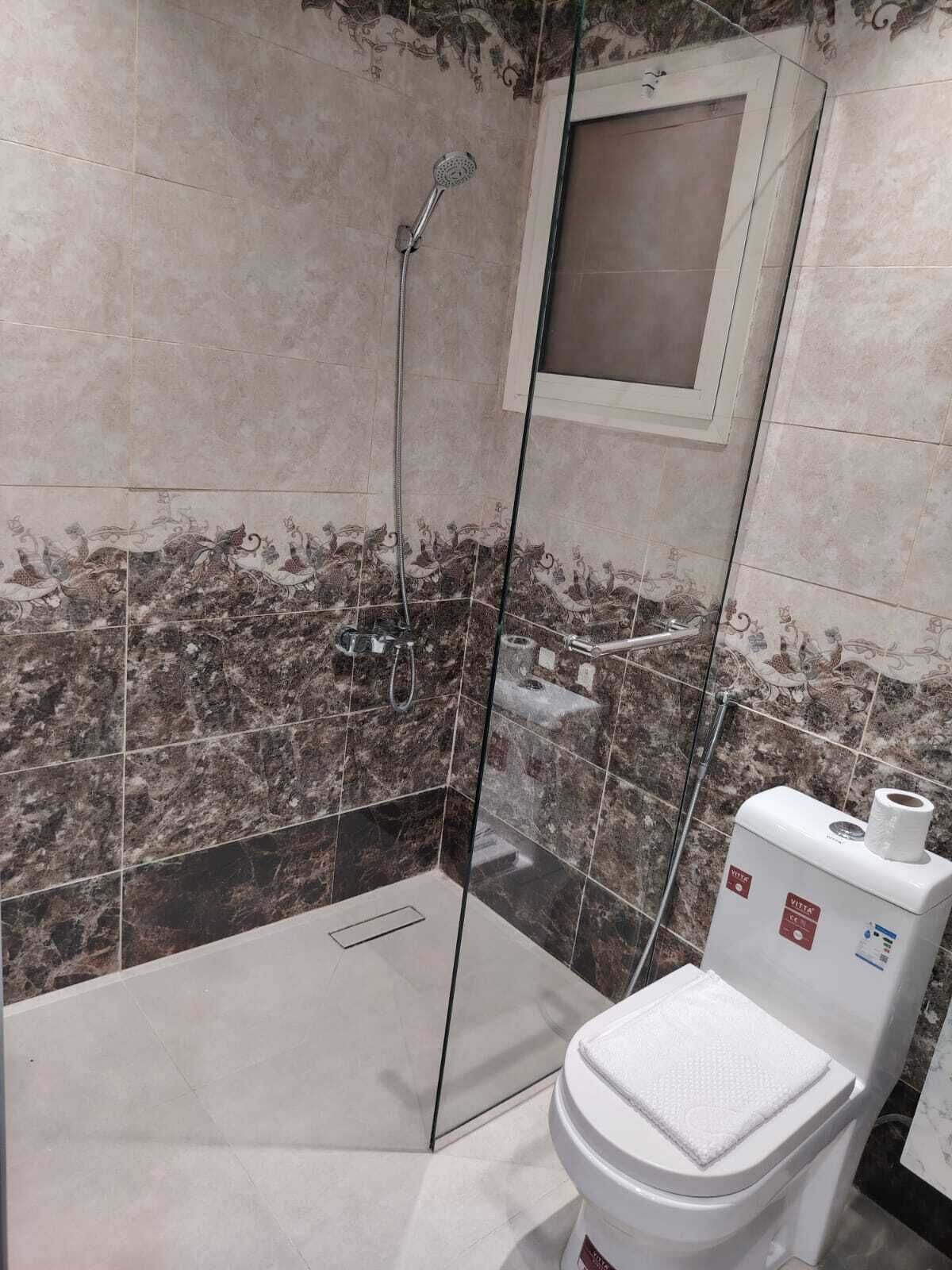 A bathroom with a shower, toilet, and a glass-enclosed shower stall.